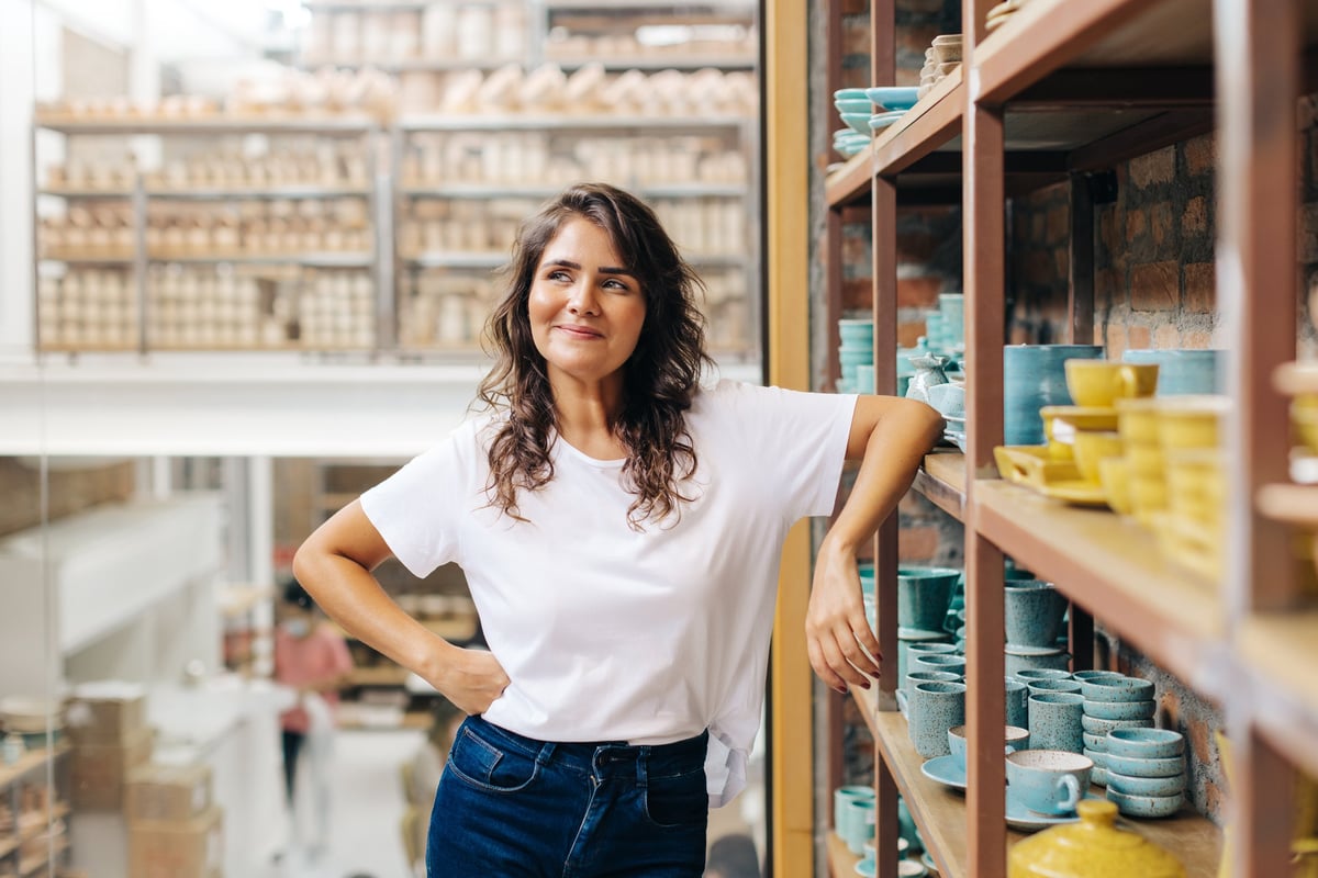 Ceramic store owner contemplating new creative ideas for her shop, cheerful young woman running successful small business