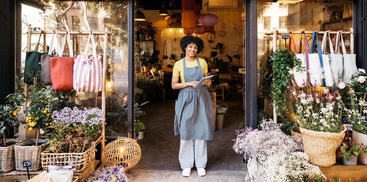 Florist owner smiling in front of her flower shop, small business entrepreneurship